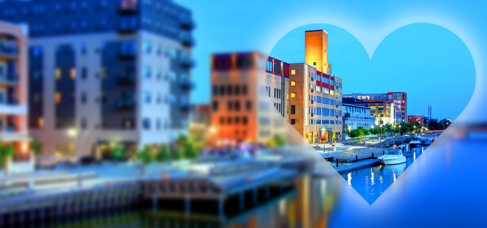 A transparent heart shape over Green Bay's City Deck area along the Fox River at night.