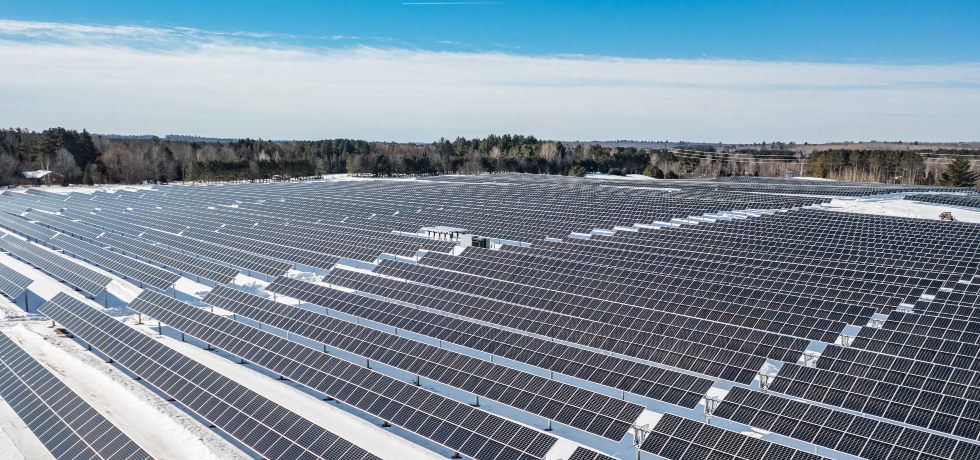 An overhead view of rows of solar panels mounted on a snow-covered field.