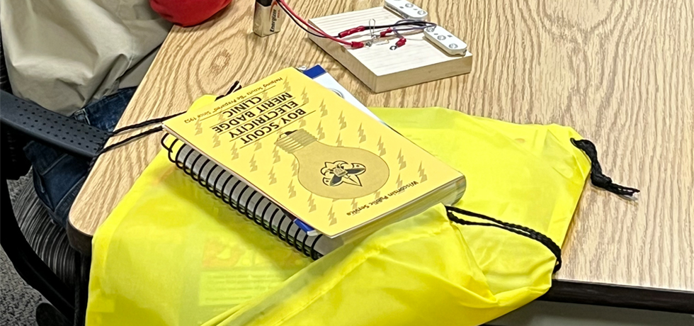 A yellow merit badge clinic manual on a yellow cinch bag.