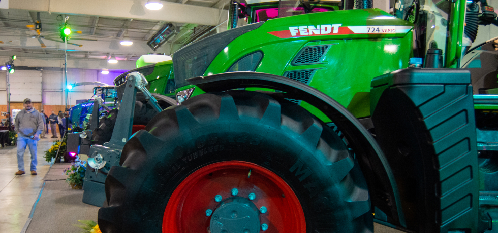 Visitors walk by a large green tractor parked inside a hangar at the WPS Farm Show.