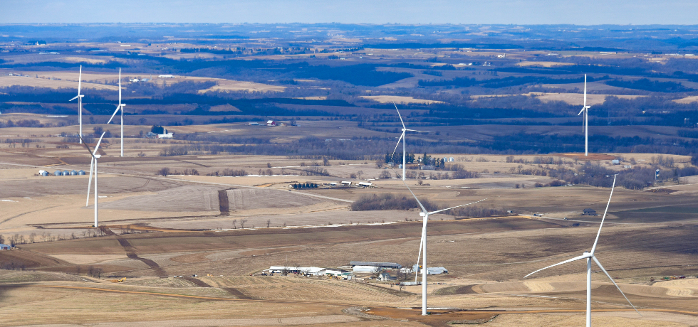 A view of seven wind turbines placed among fields in rural Wisconsin.