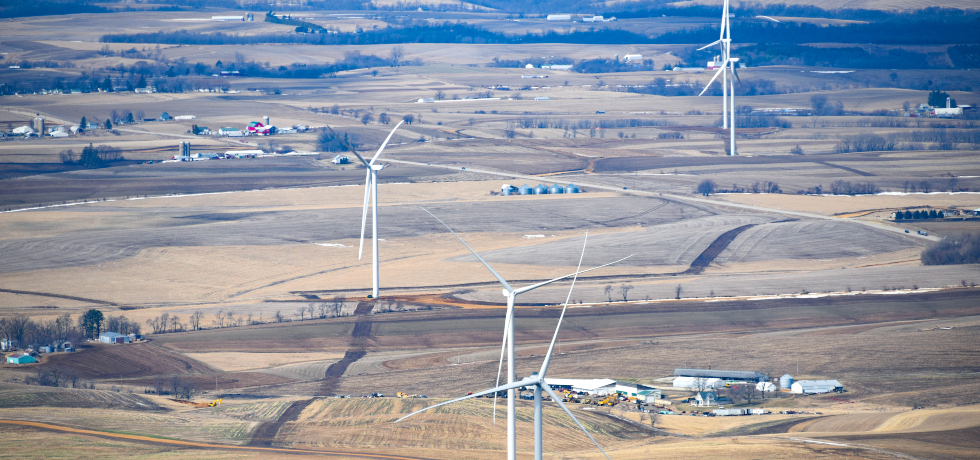 A group of wind towers installed along fields and between farms in southwestern Wisconsin.