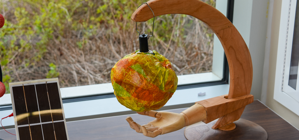 A yellow, orange and red globe hangs above a cupped wooden hand as part of a solar sculpture entry at the 27th annual WPS Solar Olympics.