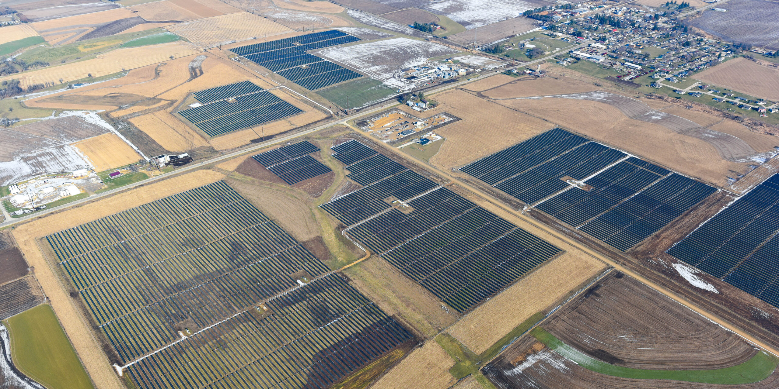 An aerial view of large blocks of solar panels installed in a rural area.