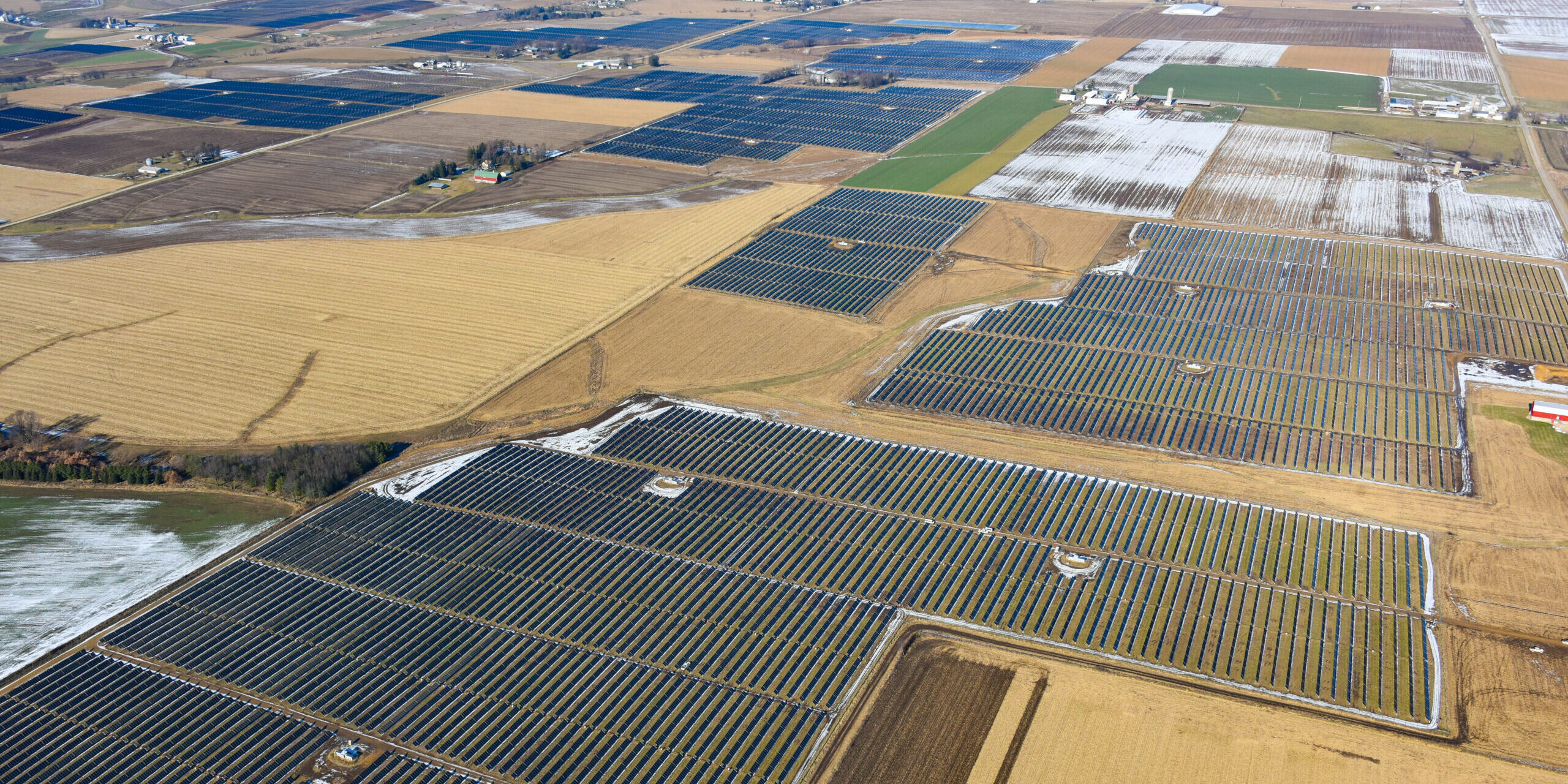 Aerial view of large blocks of solar panels installed among farm fields.
