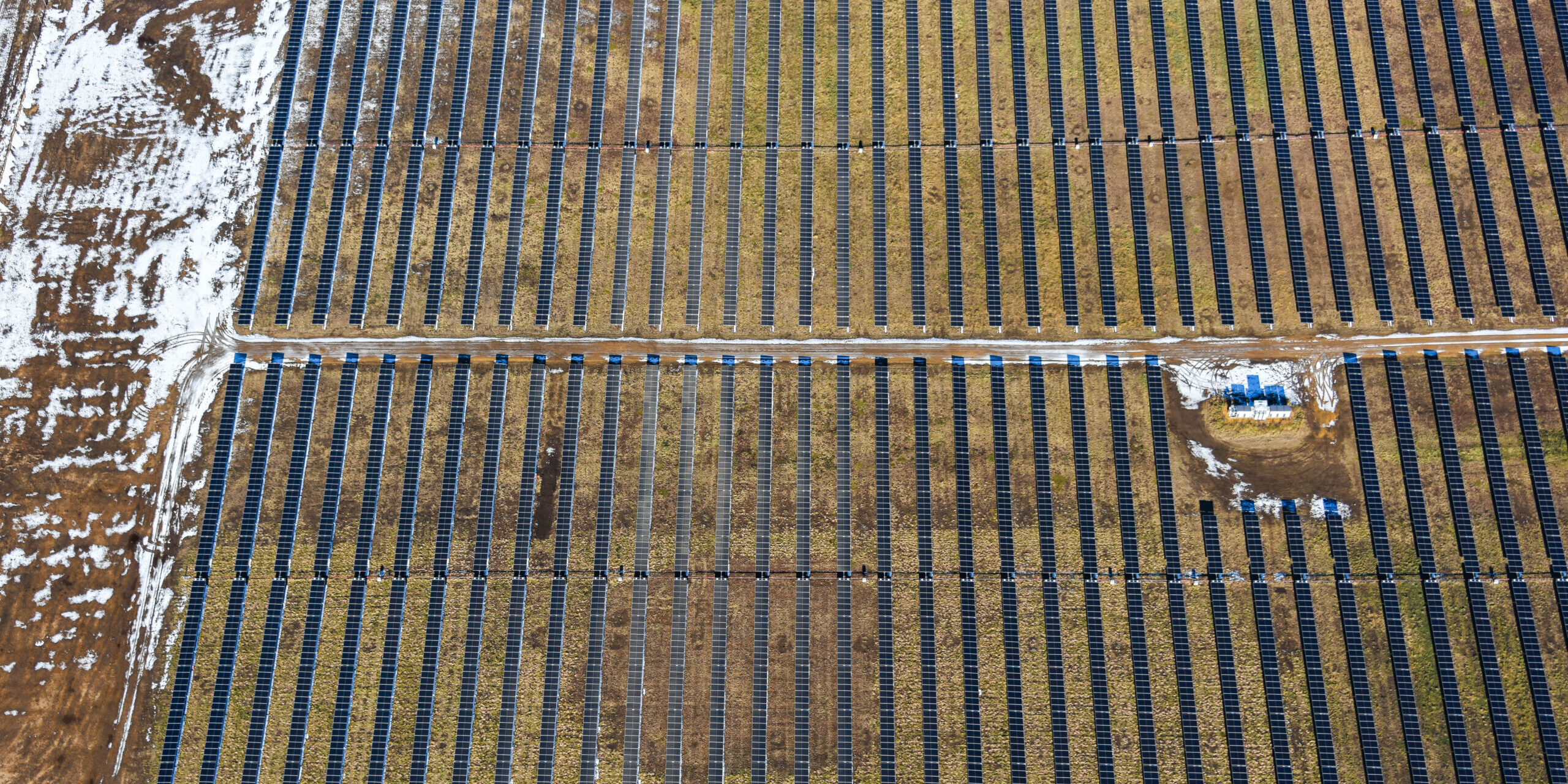 Overhead view of rows of solar panels in a rural field