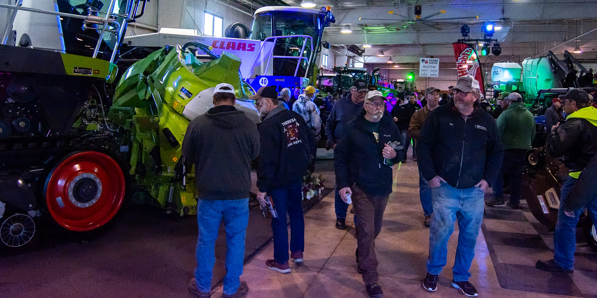 A crowd walks alongside a large farm machinery display inside the WPS Farm Show.