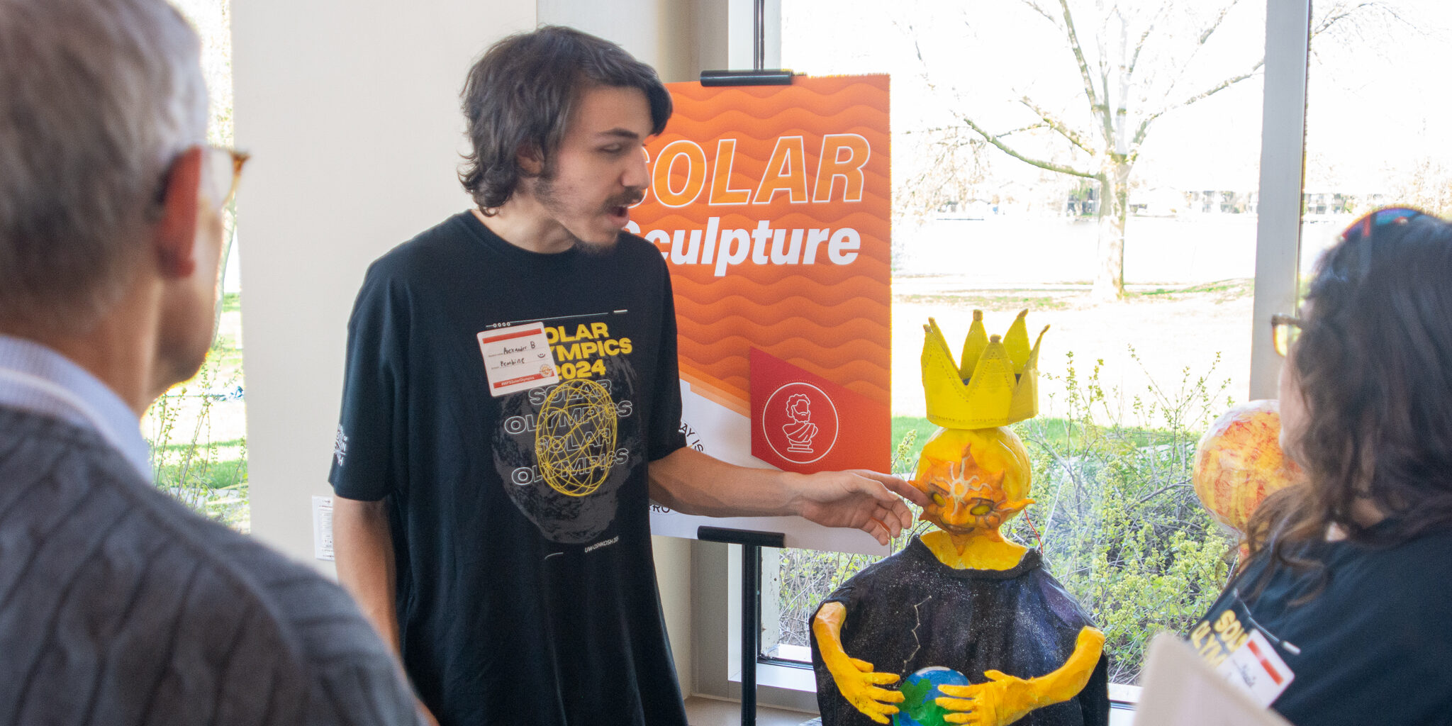 A high school boy speaks about a solar-inspired sculpture at Solar Olympics.