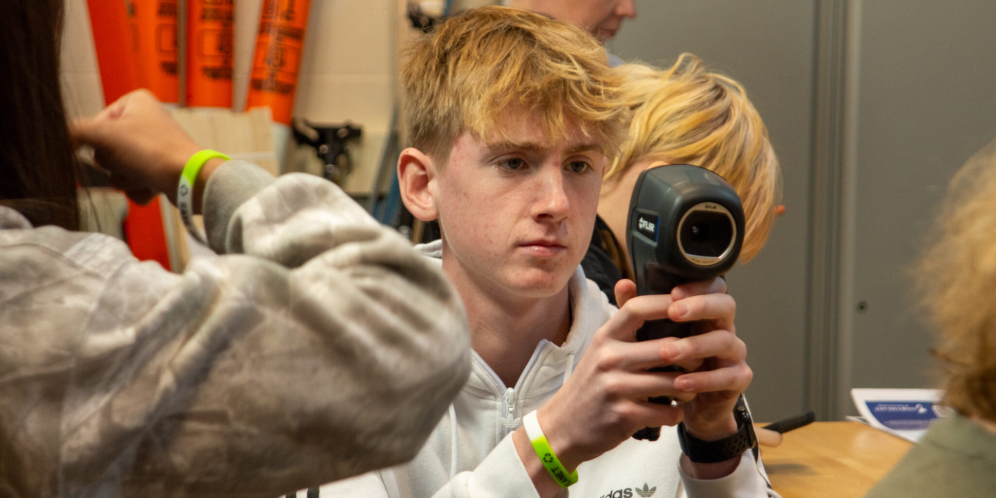 A high school student looks through a thermal imaging camera inside a classroom.