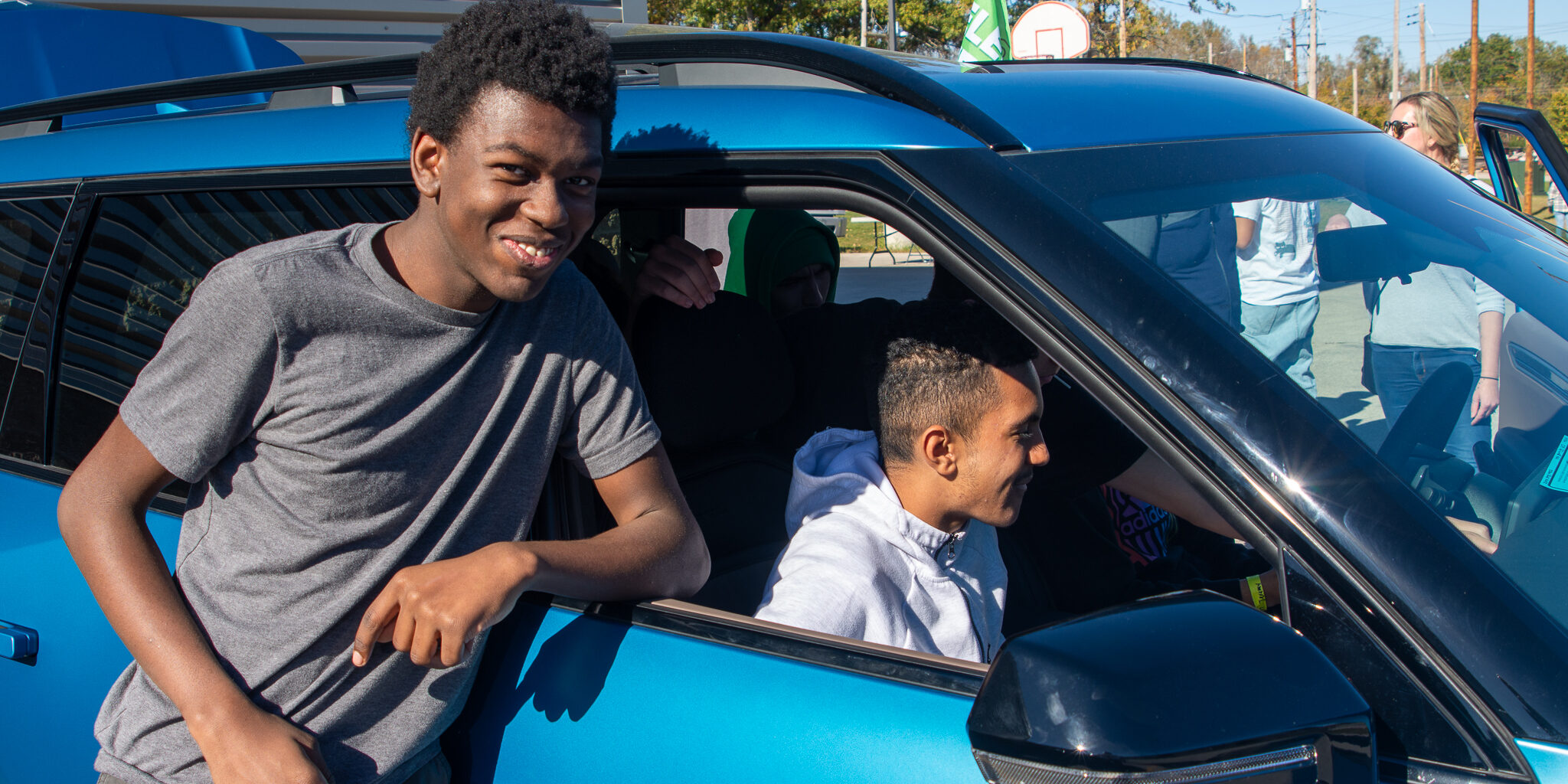 Students look at the technology inside a blue electric vehicle.