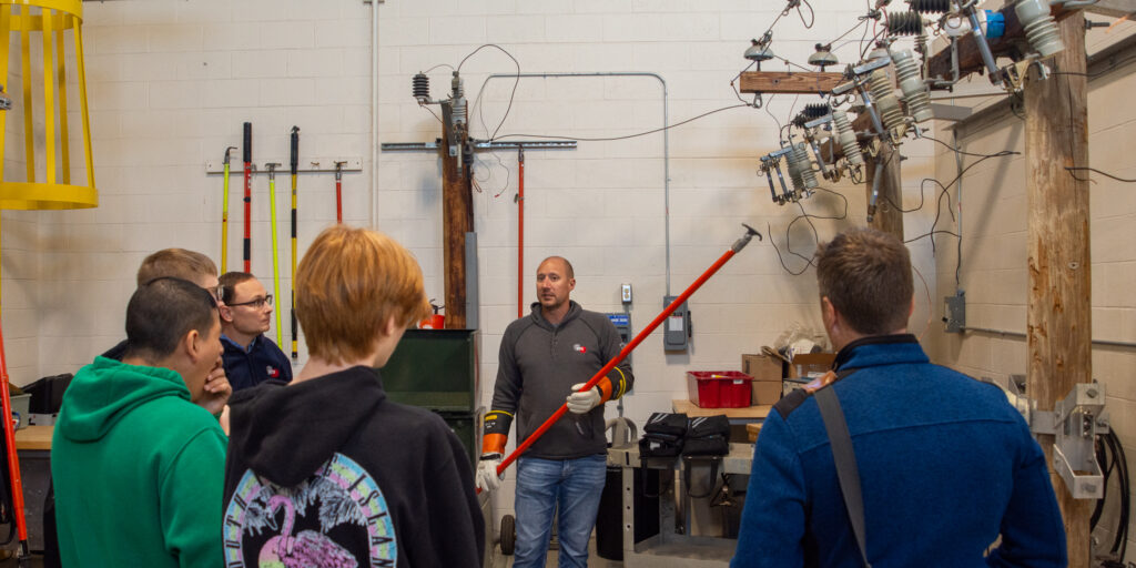 A male WPS employee demonstrates the tools and equipment used to deliver electricity inside a large learning lab.