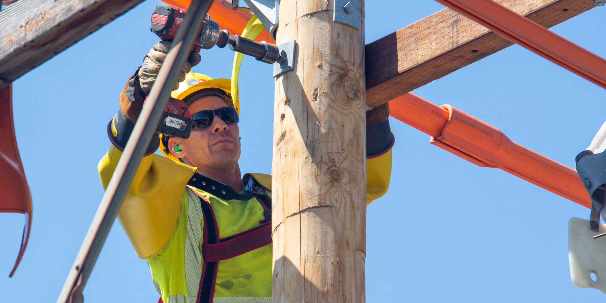 A WPS lineworker attaches a nut to a bolt at the top of a utility pole.