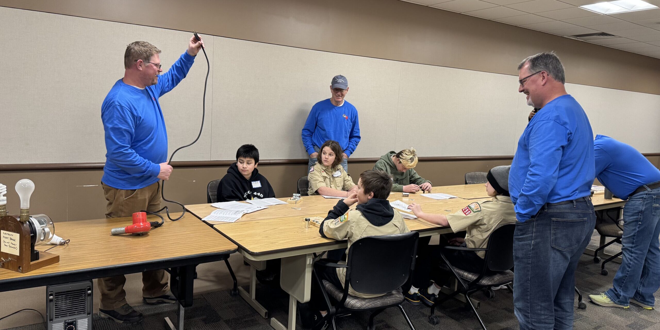 A WPS employee discusses how electricity flows to a household hair dryer with Scouts during an electricity merit badge clinic.