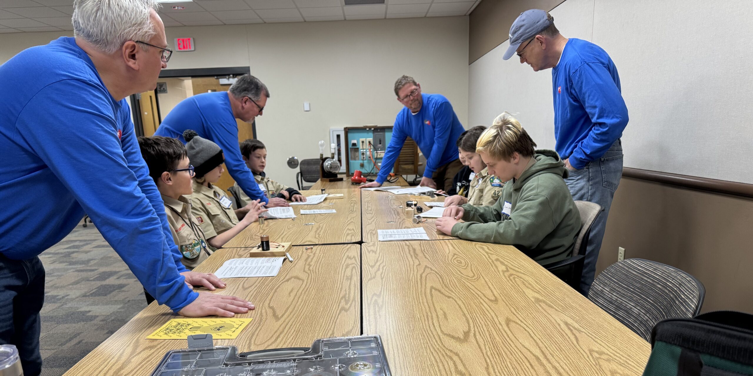 WPS employees watch as Scouts put together electric circuits while sitting at long tables.