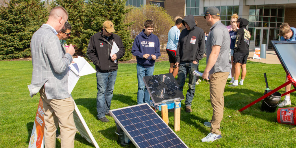 Two high school students speak with WPS judges about a solar-powered water heater.
