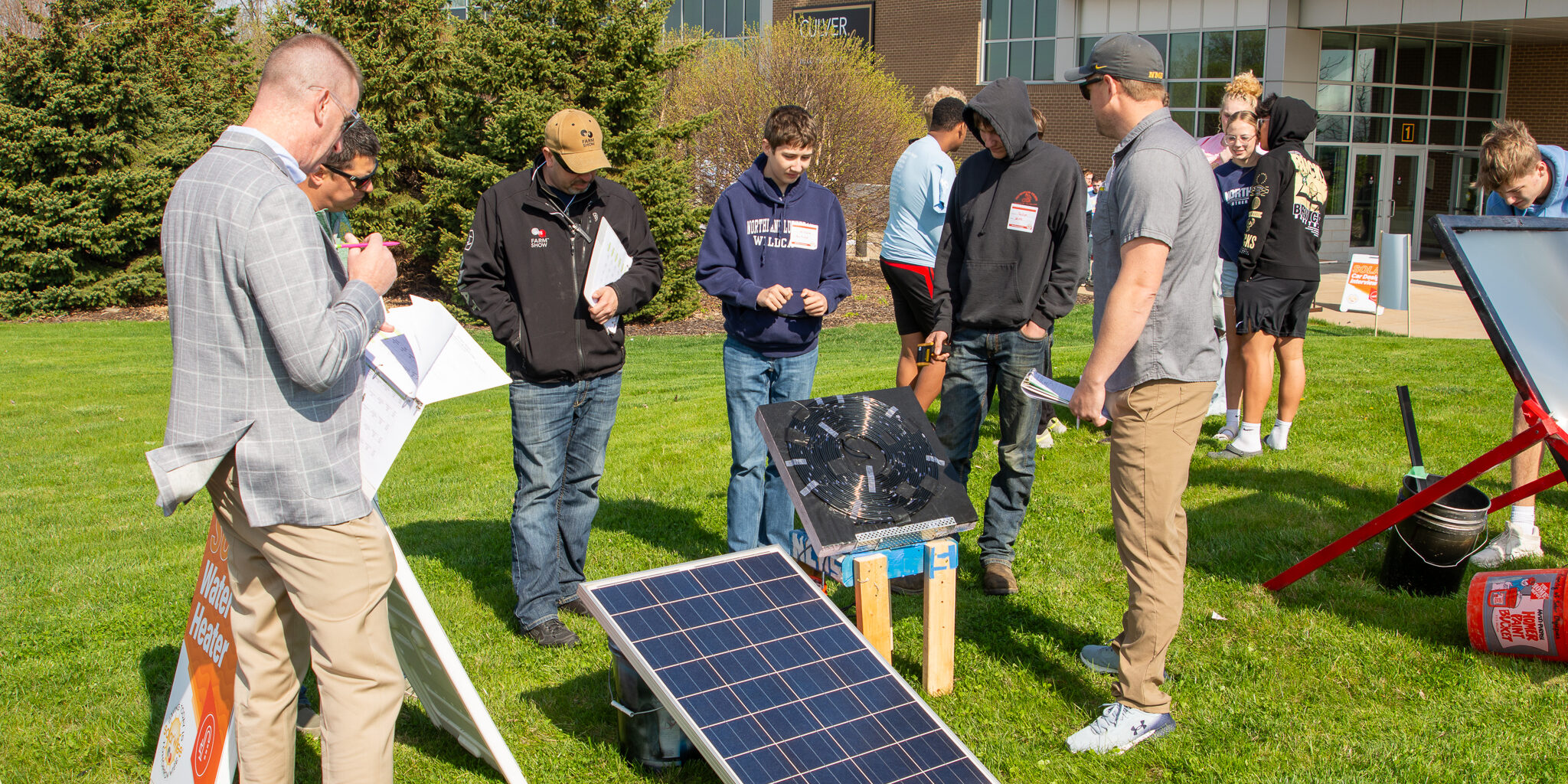 Two high school students speak with WPS judges about a solar-powered water heater.