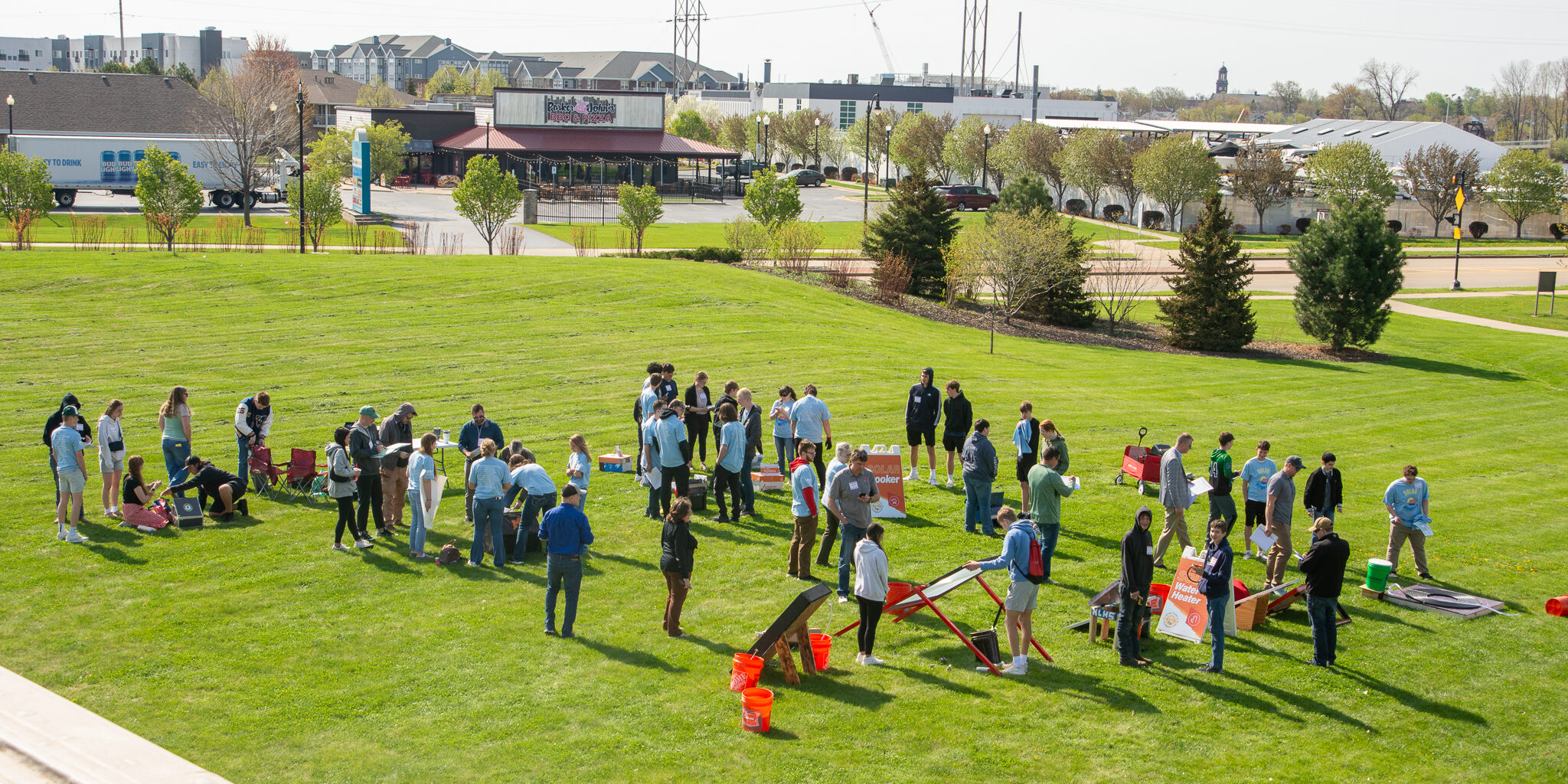 Several students set up solar-powered projects on a large grass lawn.