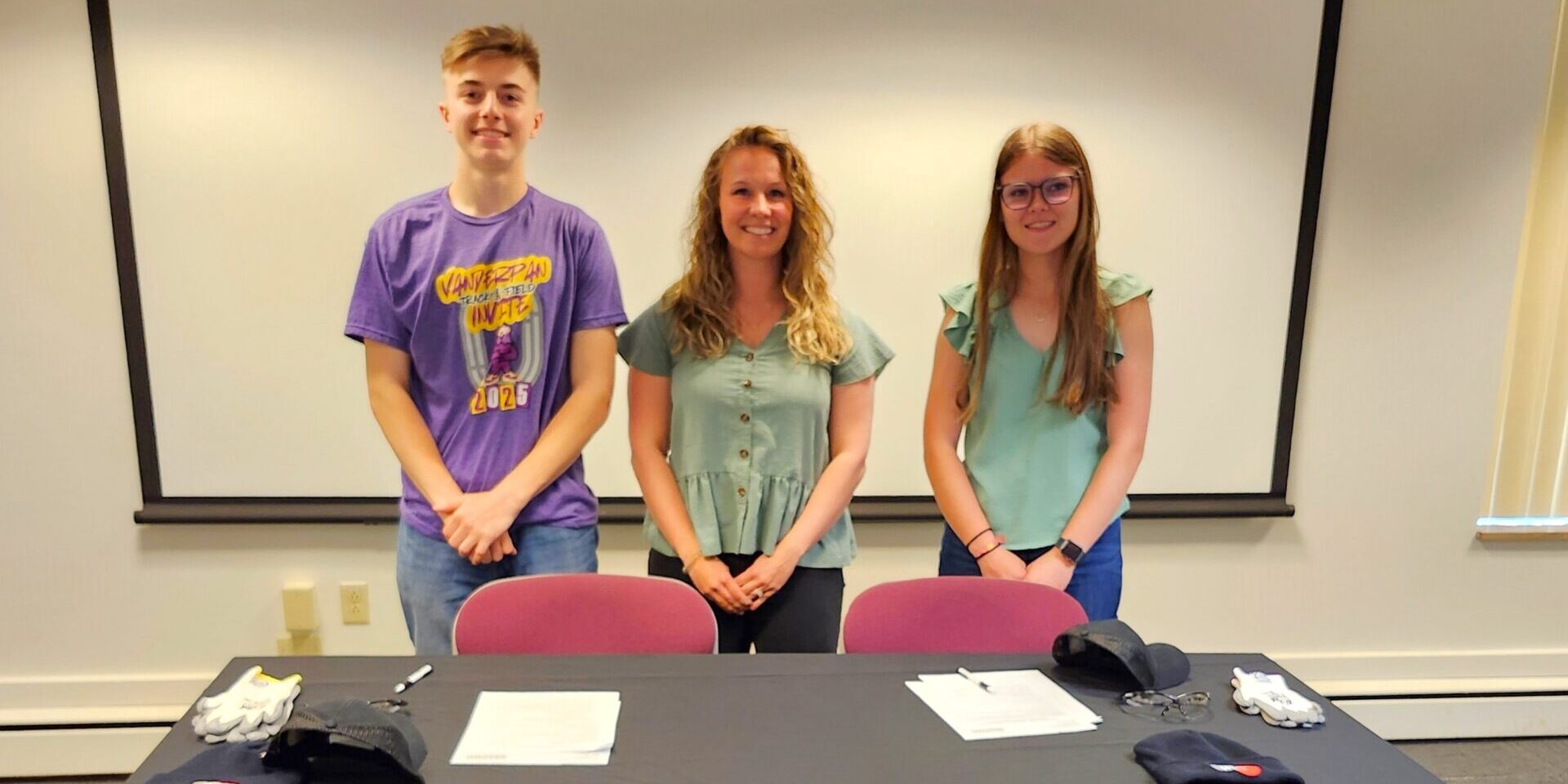 A pair of high school students stand behind a table covered by a black WPS tablecloth
