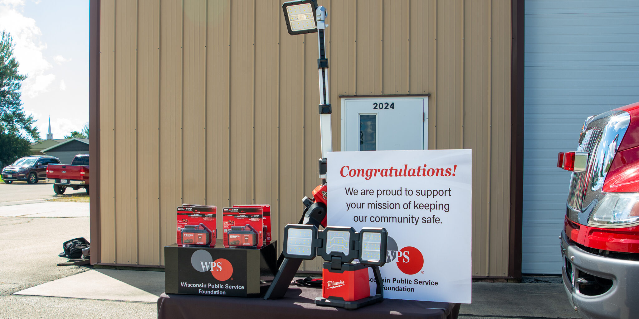 Emergency scene lights and a congratulatory sign rest on a table with a black WPS Foundation tablecloth on it.