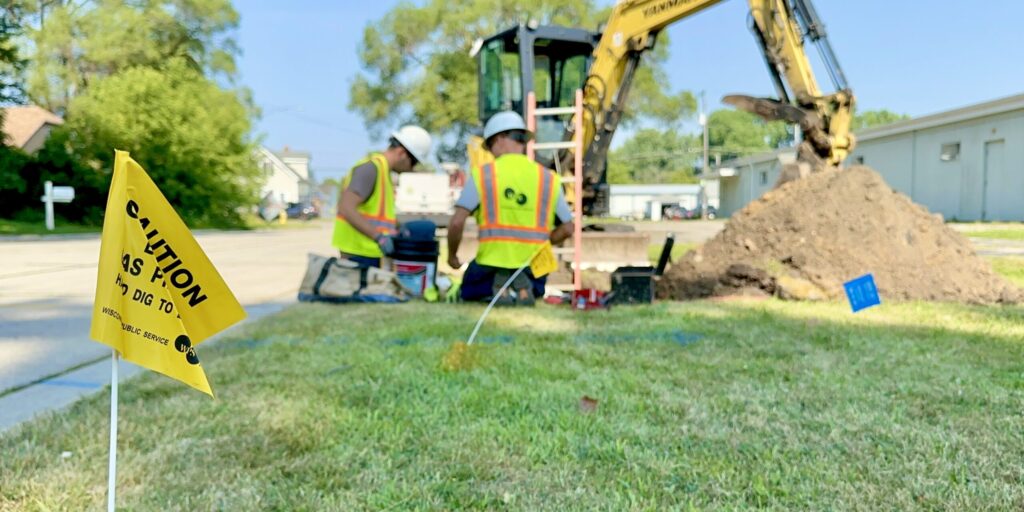 A yellow flag marks an underground natural gas line as WPS workers work on a digging project.