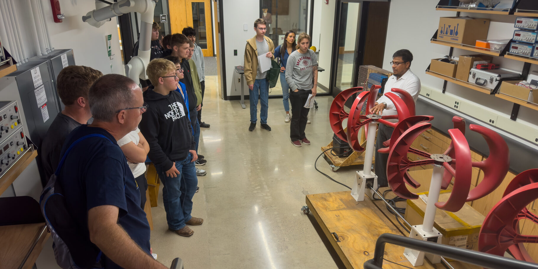 A group of high school students listens to a professor explain a design for vertical wind turbines.