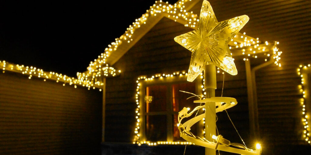 White holiday light decorations arranged around the front of a house with an illuminated star in the right foreground.