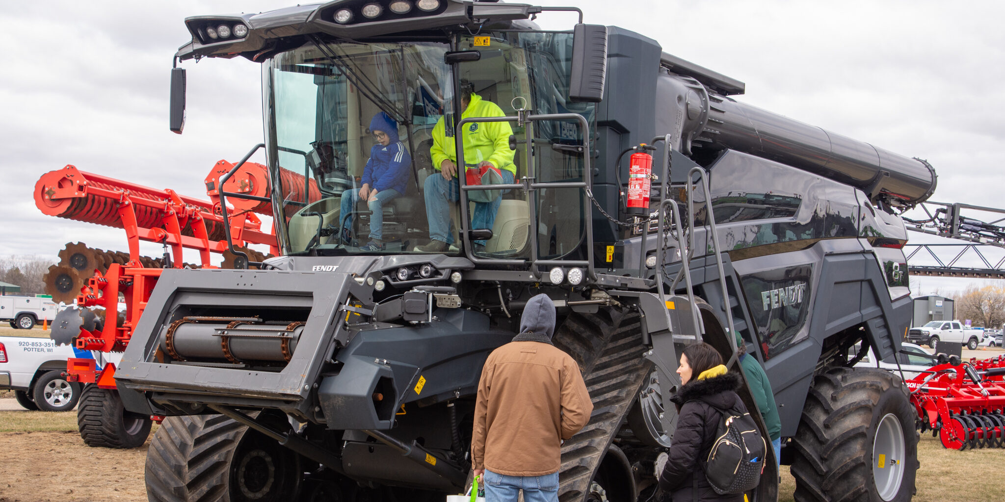 People sit inside a large combine harvester on display at the WPS Farm Show.