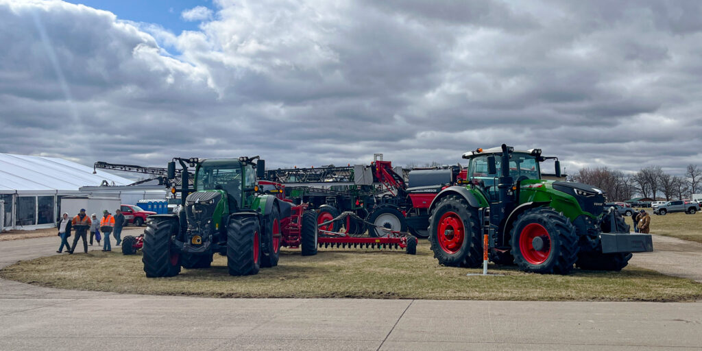 Large farm machinery parked on a grassy area surrounded by concrete walkways.