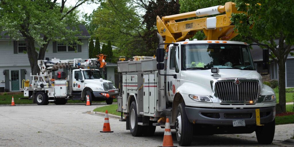 Two large WPS trucks parked along a roadway with traffic cones next to them.
