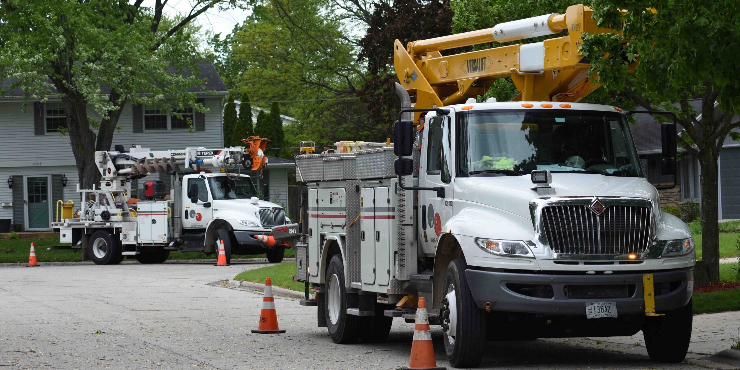 Two large WPS trucks parked along a roadway with traffic cones next to them.