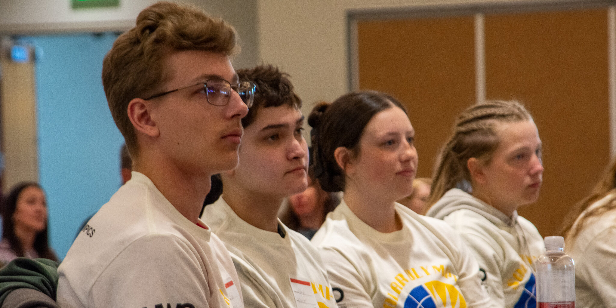 A group of male and female high school students listens to a presentation during the 30th annual Solar Olympics.