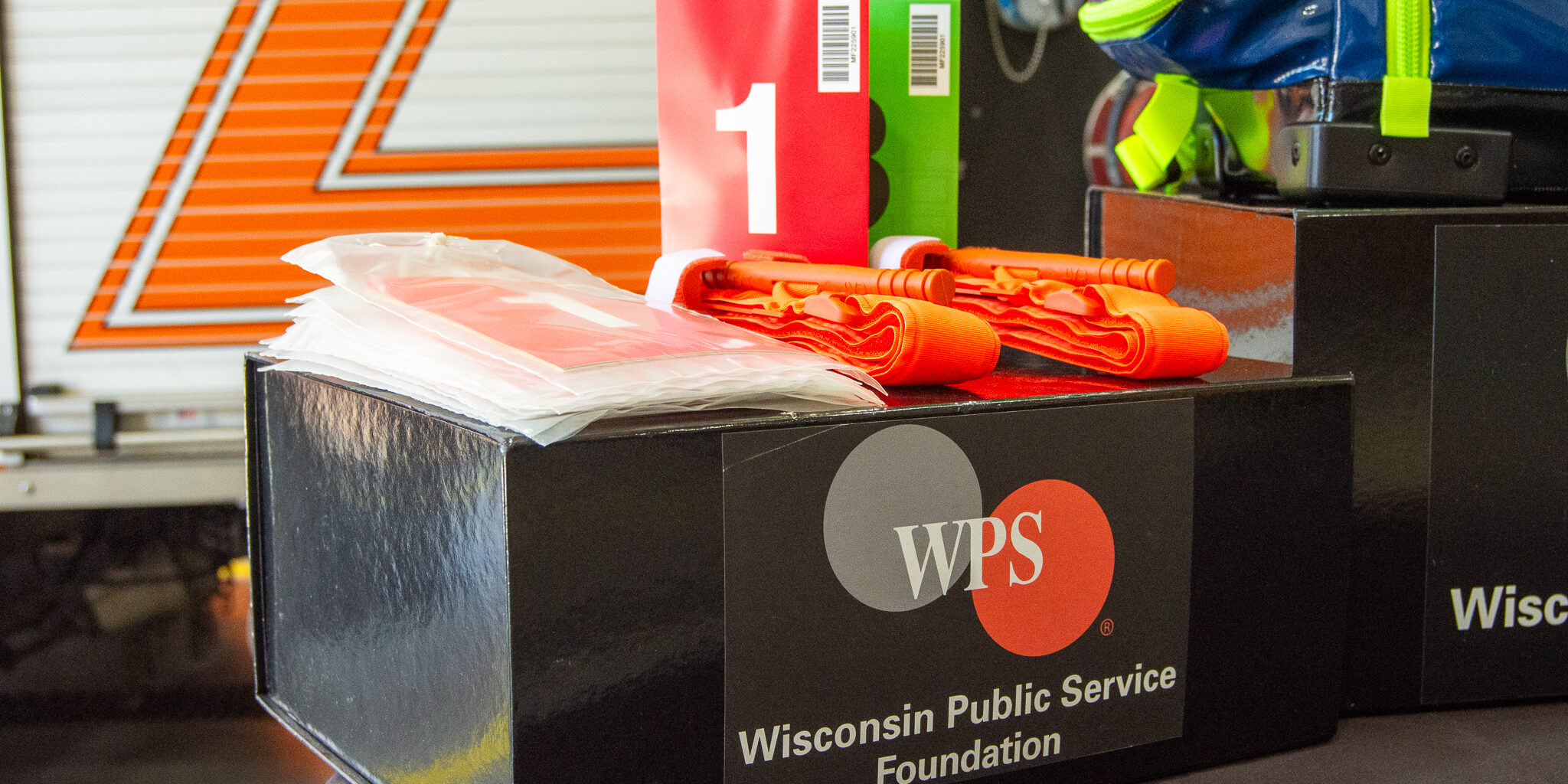 Emergency triage tags and tourniquets arranged of top of a small box with the WPS Foundation logo on the front.