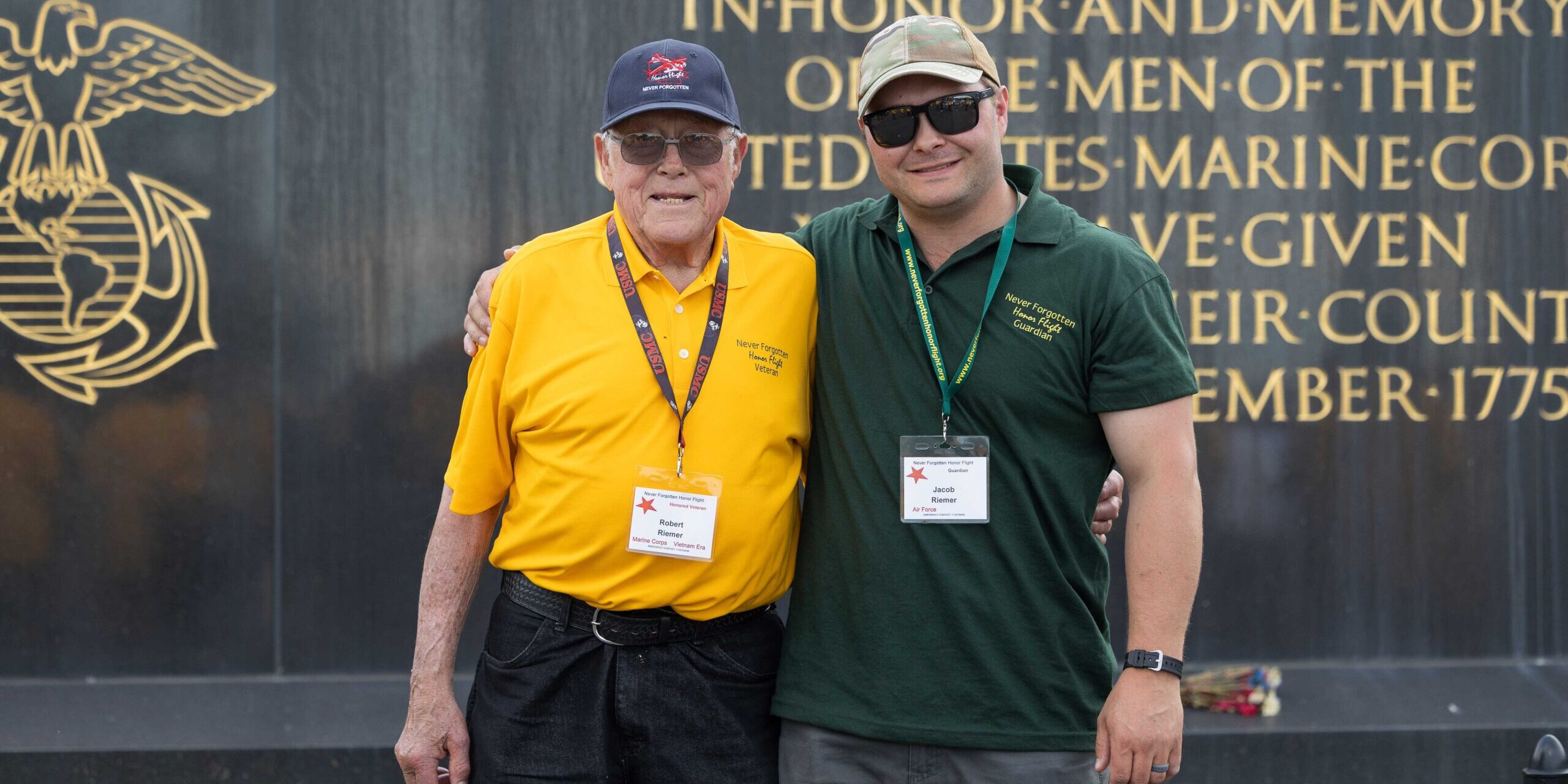 Two men stand for a photo in front of the U.S. Marine Corps War Memorial.